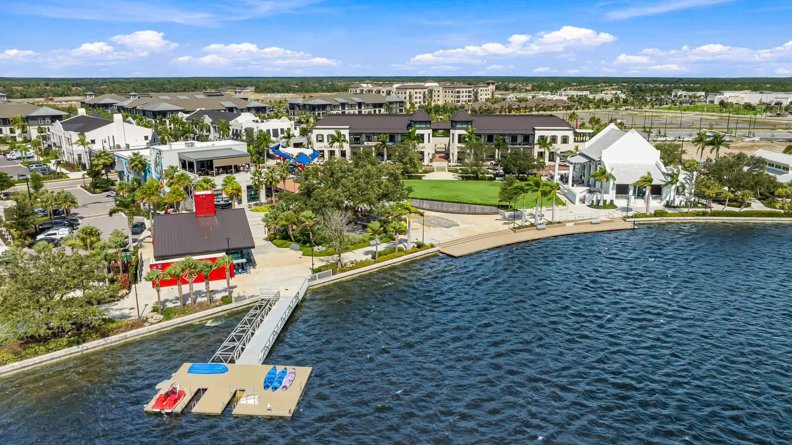 Aerial view of the lake in Downtown Wellen Park with a dock, lawn and surrounding homes