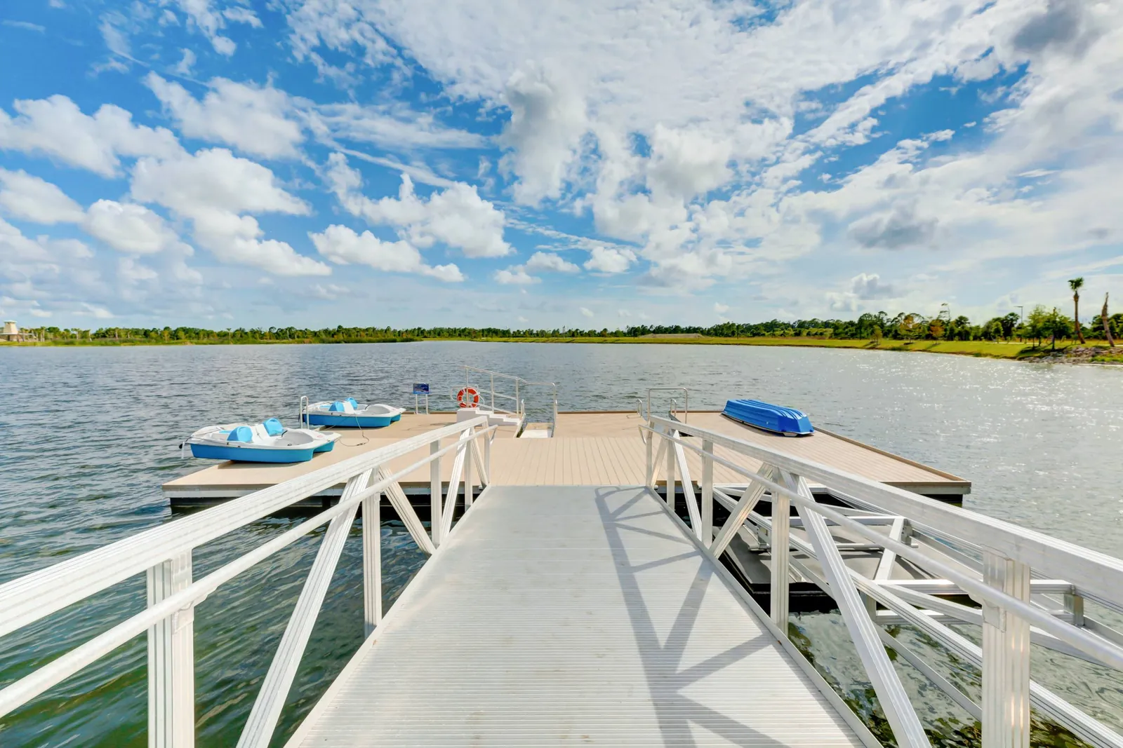 White dock reaching into the lake with pedal boats tied alongside under a cloudy sky in Wellen Park