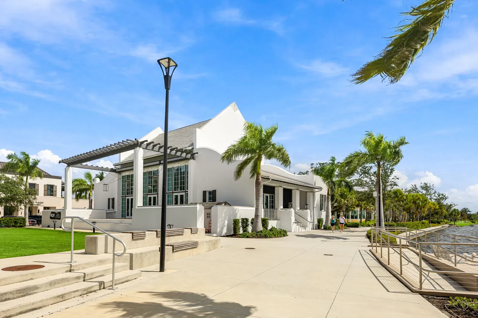White gabled lakefront pavilion with a trellis, steps and palms in Downtown Wellen Park